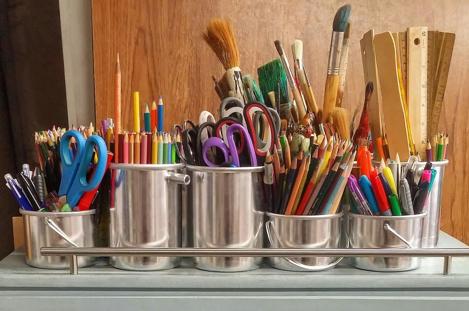 an assortment of art supplies in tin cans on top of a table