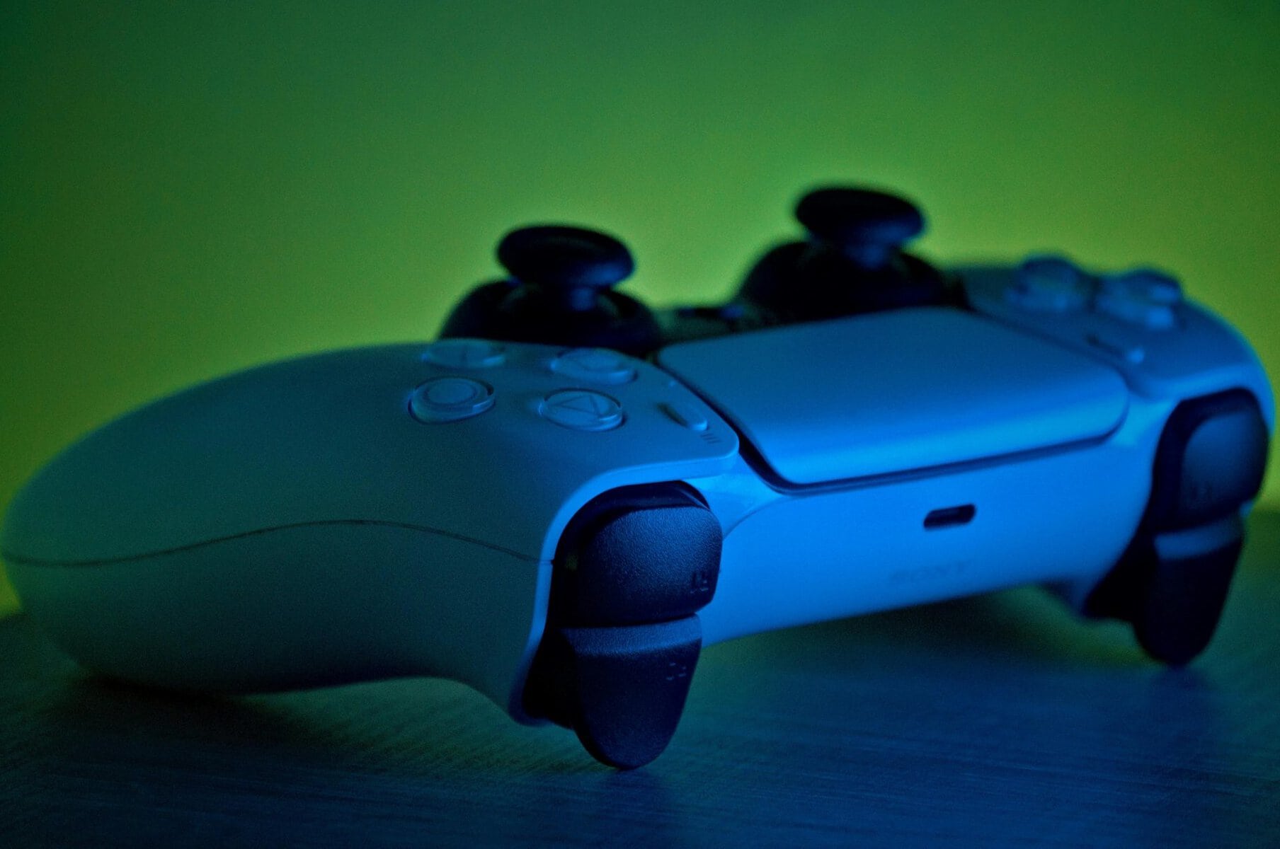 a PS5 controller is lit up in front of a green background