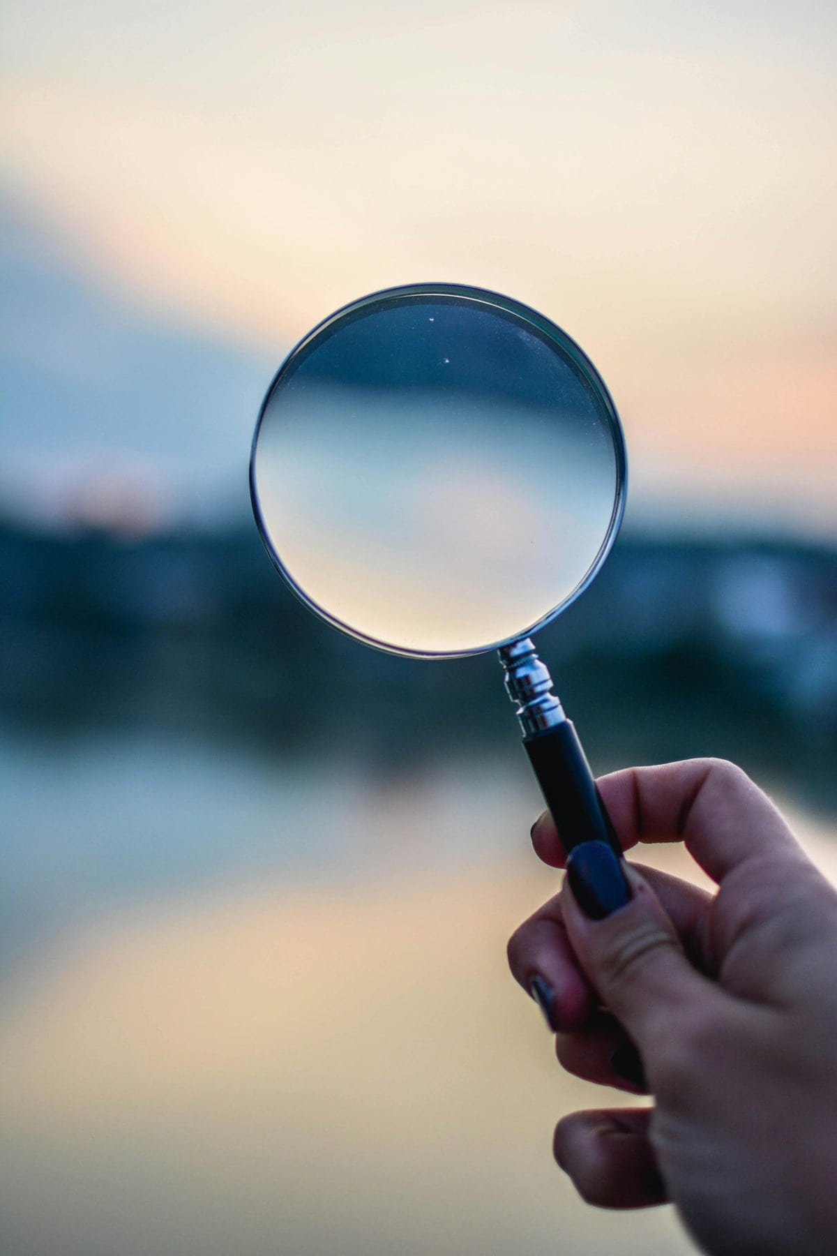 a person holding a magnifying glass in front of a body of water